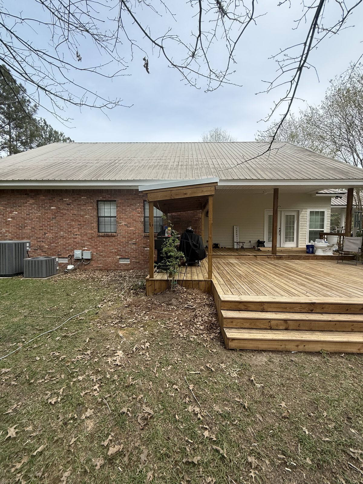 New wood deck with wide steps built off the back of a brick home